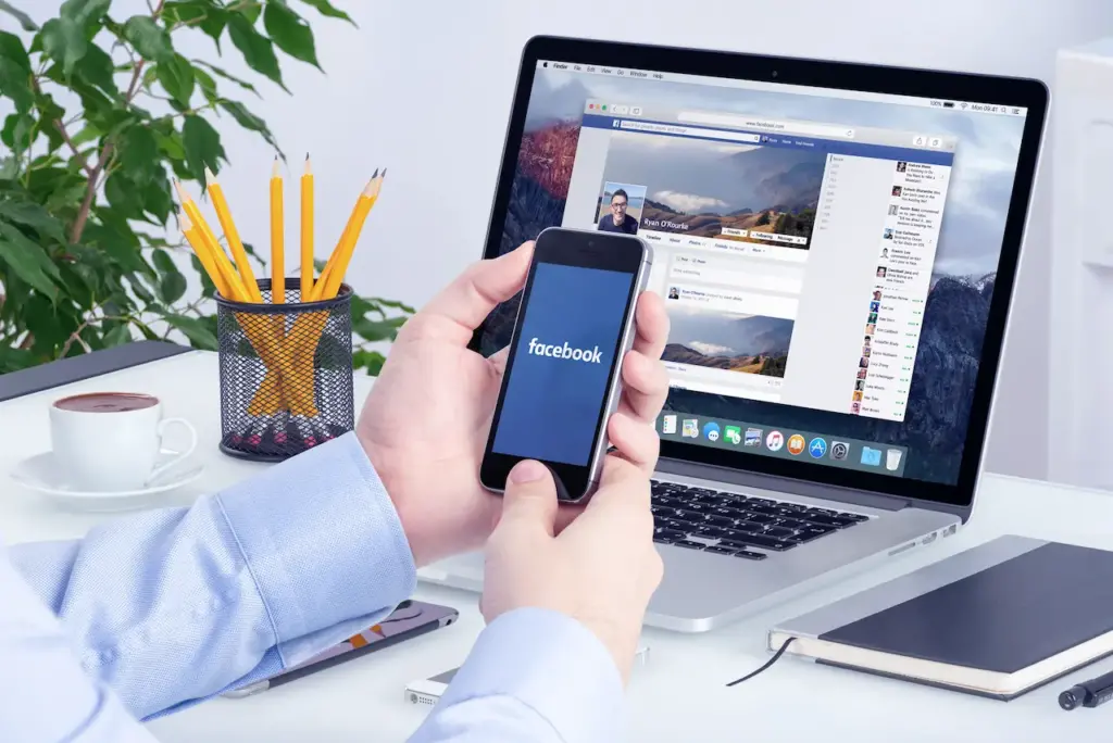 Person Using Facebook Using A Phone and Laptop